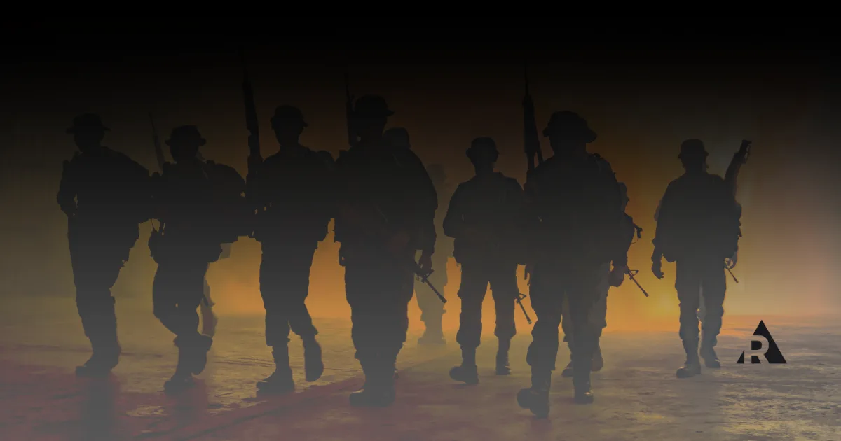 Silhouetted soldiers walking through dust at sunset