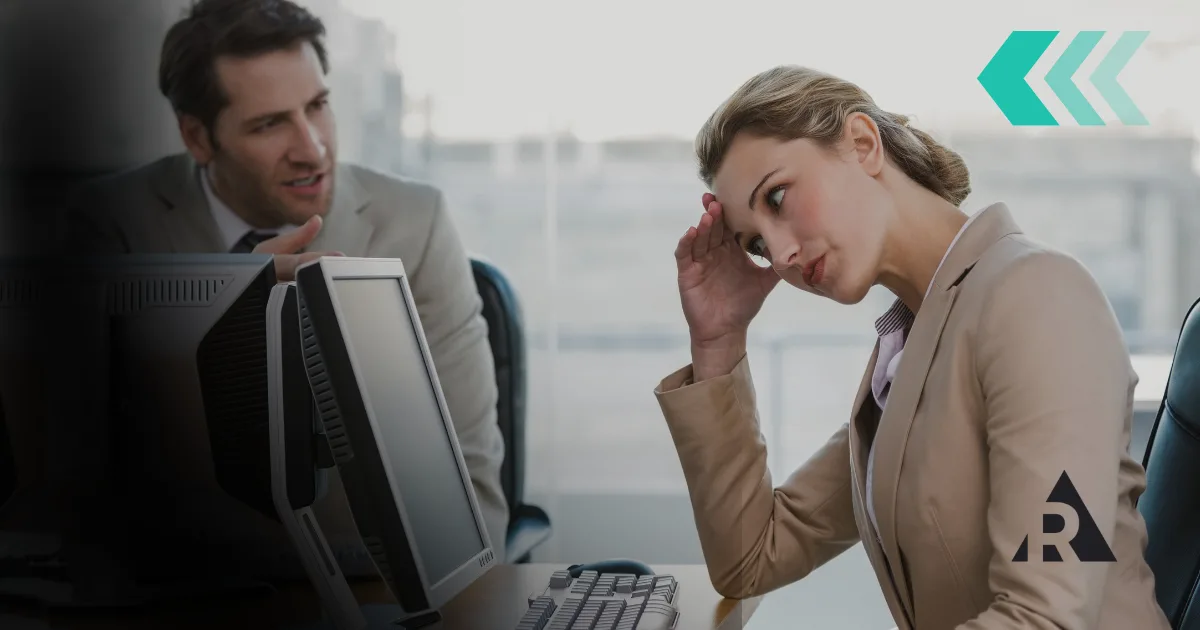 Professional looking frustrated at a desk while a coworker speaks nearby, representing resistance to Agile adoption and organizational change.